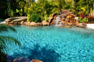 pool with rock water feature and tropical plants